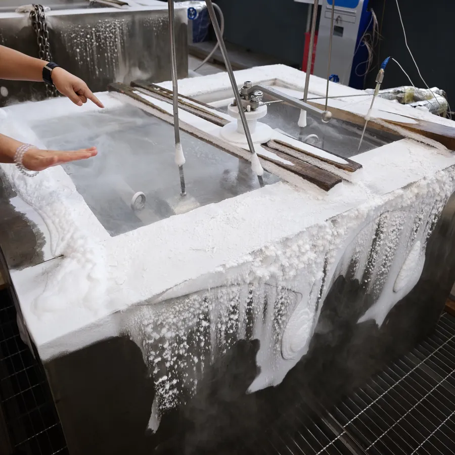 Cryogenic valve parts immersed in a liquid-nitrogen test bath, the tank walls frosted and the cryogen boiling off